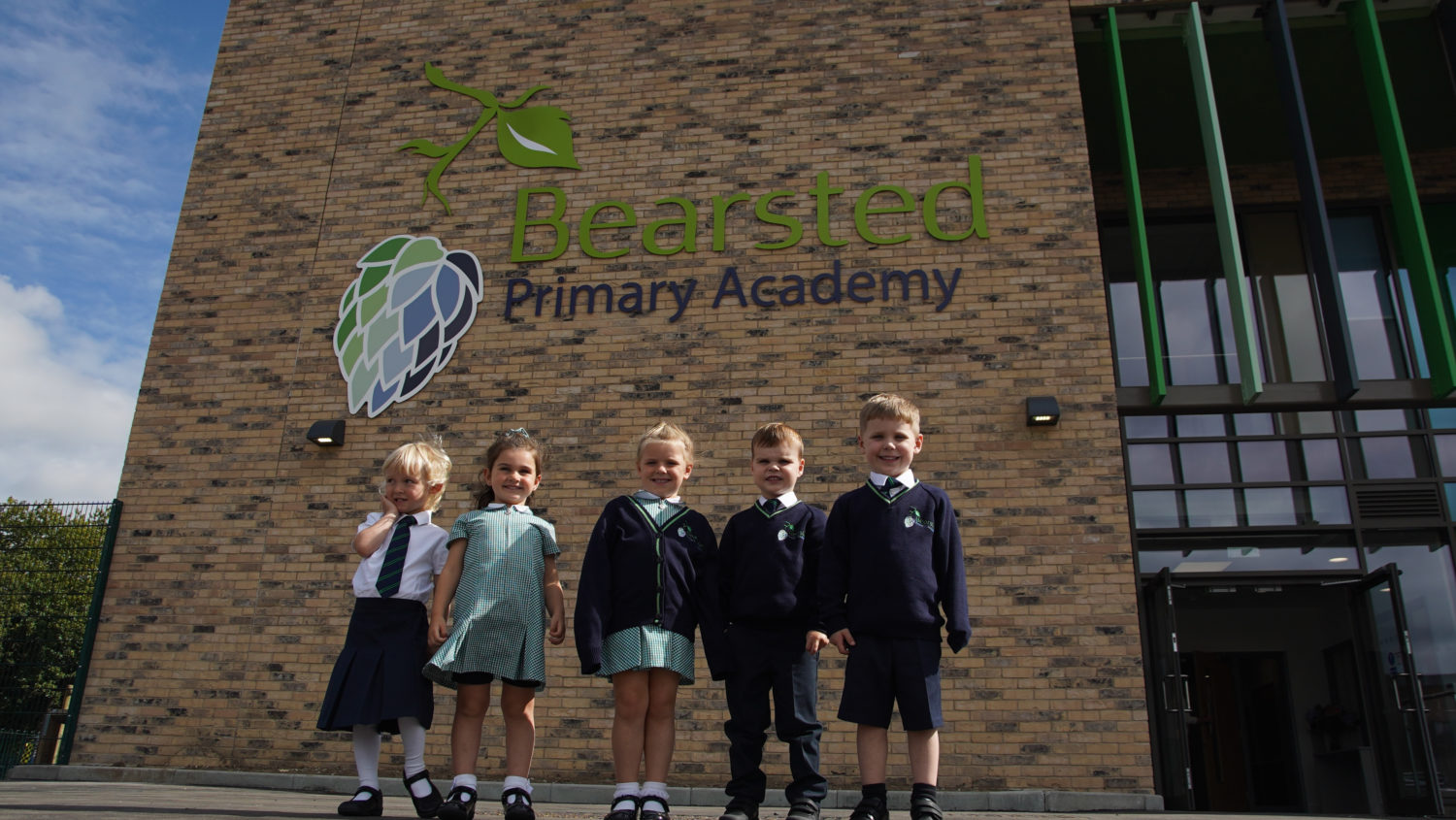 A group of children stood under the outside Bearsted Primary Academy sign