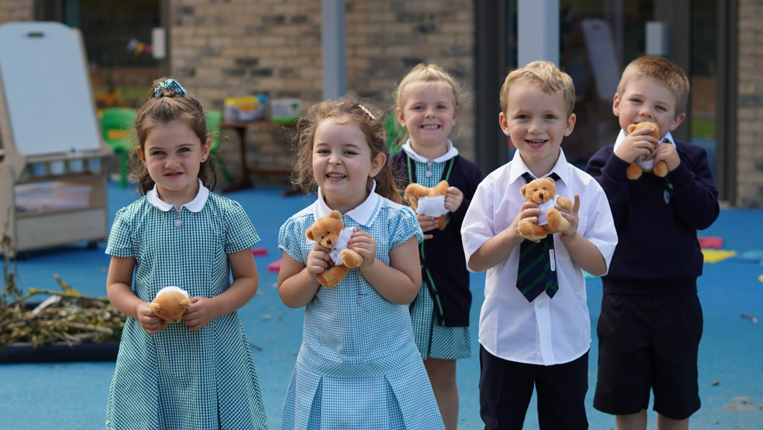 A group of children outside holding small teddy bears
