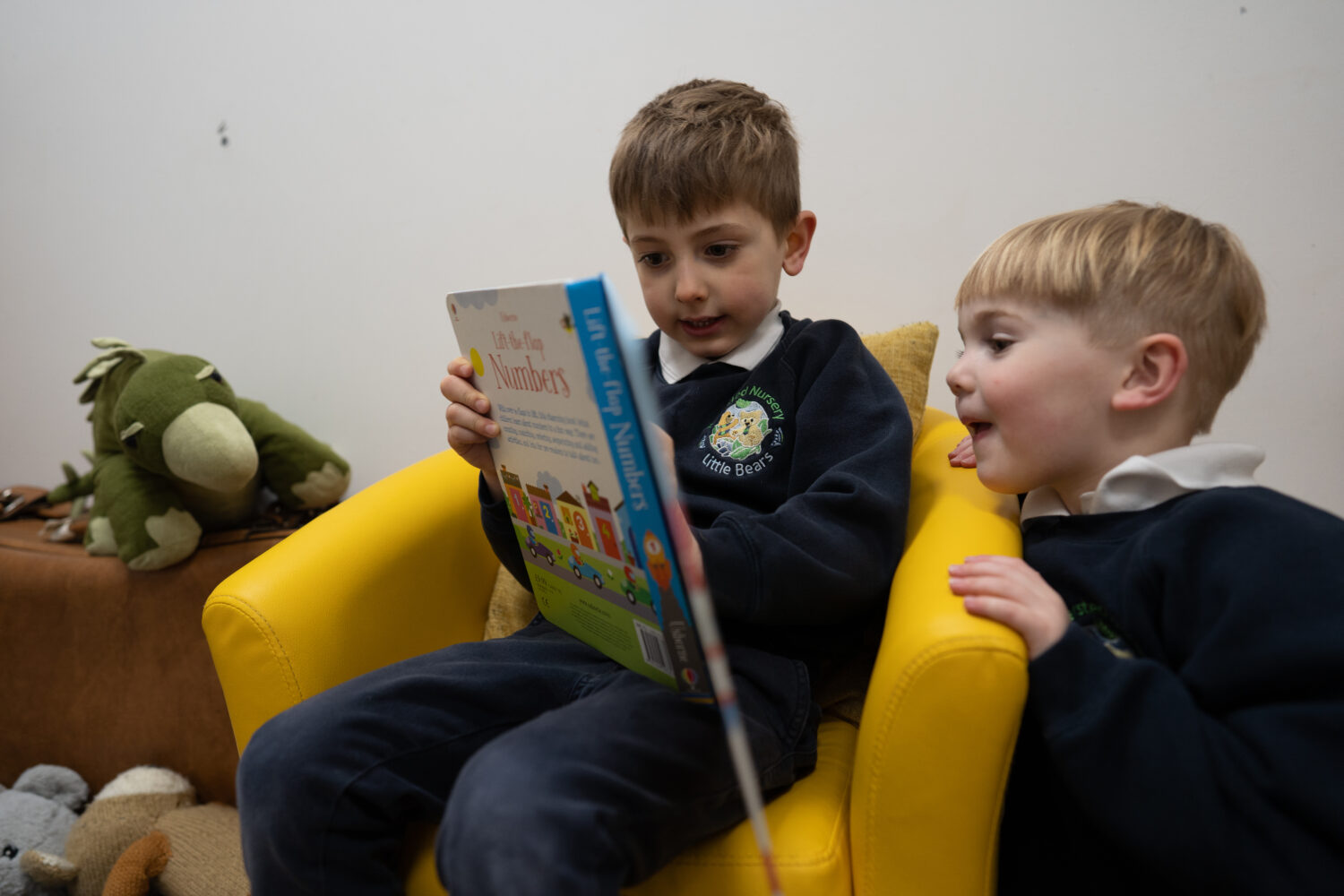 Two young boys from Little Bears Nursery are pictured sat down about to read a storybook together.